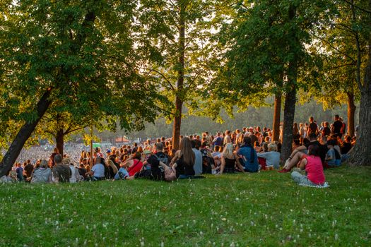 Televisiekijkers bespreken thuis de mogelijke boycot van het Songfestival terwijl nieuwsreacties op een smartphone zichtbaar zijn